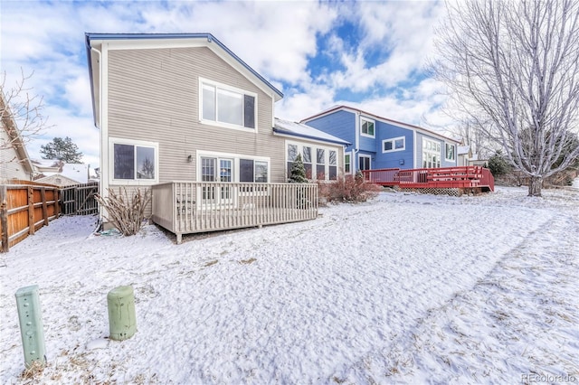 snow covered back of property with a wooden deck