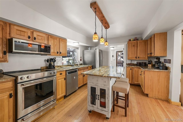27802 Shadow Mountain Dr, Conifer, CO 80433 - kitchen with appliances with stainless steel finishes, a breakfast bar area, light stone countertops, a center island, and light wood finished floors