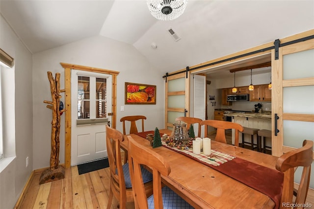 27802 Shadow Mountain Dr, Conifer, CO 80433 - dining area with a barn door, light wood-type flooring, vaulted ceiling, and baseboards