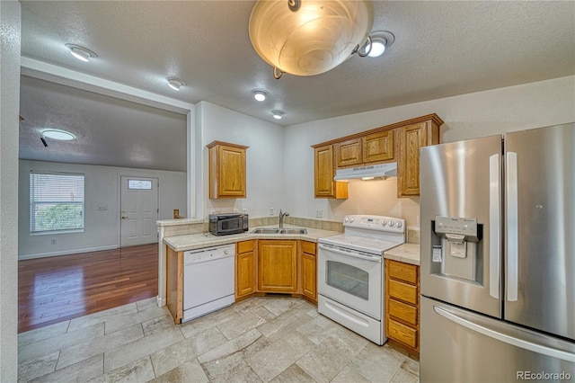 kitchen featuring white appliances, a textured ceiling, light hardwood / wood-style flooring, and sink