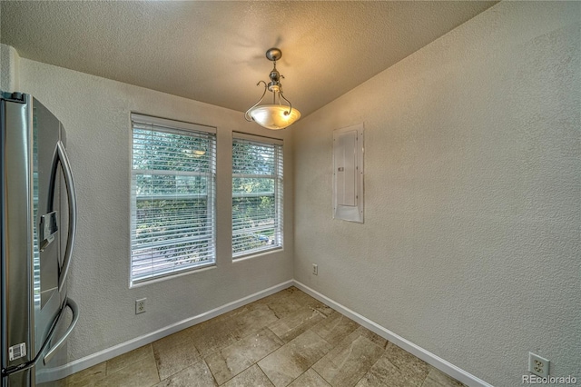 unfurnished dining area with a wealth of natural light, lofted ceiling, electric panel, and a textured ceiling