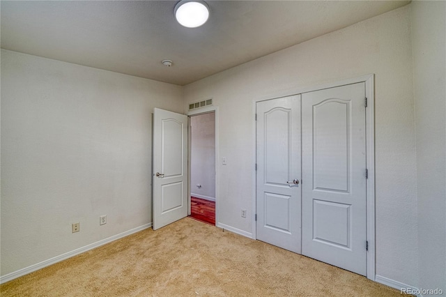 unfurnished bedroom featuring a closet and light carpet