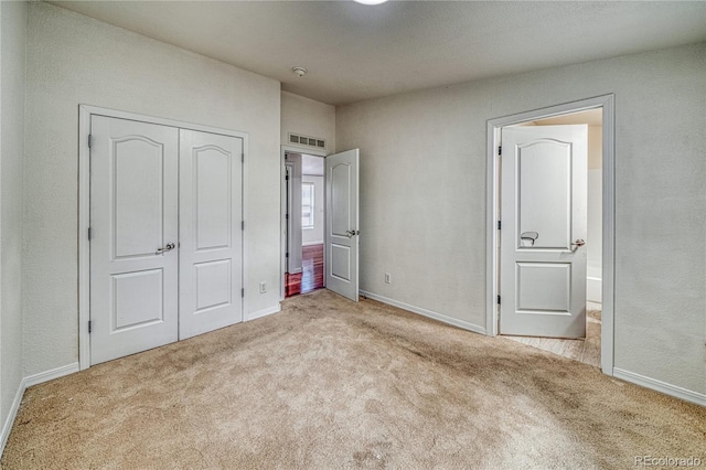 unfurnished bedroom featuring light carpet and a closet