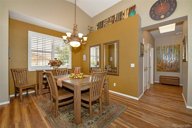 dining area featuring hardwood / wood-style flooring, a notable chandelier, and lofted ceiling