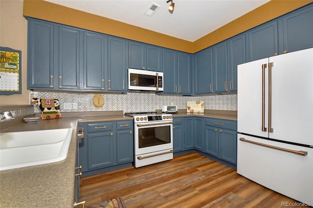 kitchen with backsplash, dark hardwood / wood-style flooring, blue cabinets, sink, and white appliances