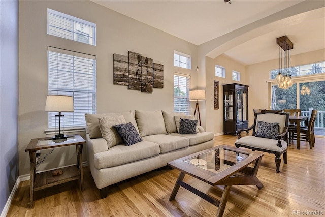 3120 Redhaven Way, Highlands Ranch, CO 80126 - living area with an inviting chandelier, arched walkways, light wood-style floors, and baseboards