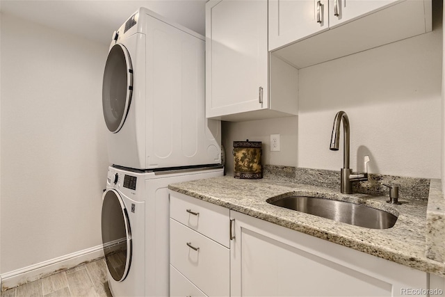 3120 Redhaven Way, Highlands Ranch, CO 80126 - laundry area featuring cabinet space, a sink, baseboards, stacked washer / dryer, and light wood-type flooring