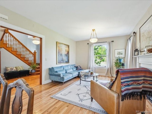 living room featuring wood finished floors, stairway, and baseboards