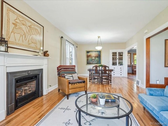 living room with light wood finished floors, a fireplace, and baseboards