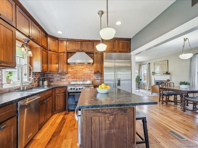 kitchen with high quality appliances, range hood, dark countertops, healthy amount of natural light, and recessed lighting
