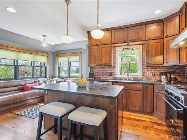 kitchen featuring high end stove, dark countertops, open floor plan, light wood-type flooring, and recessed lighting