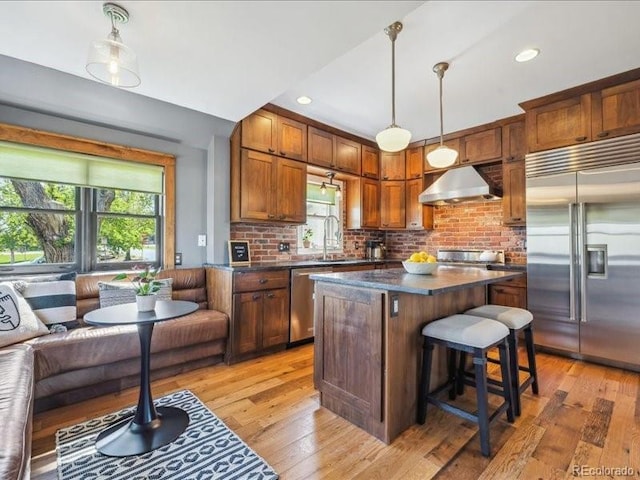kitchen featuring appliances with stainless steel finishes, under cabinet range hood, dark countertops, light wood-style flooring, and recessed lighting