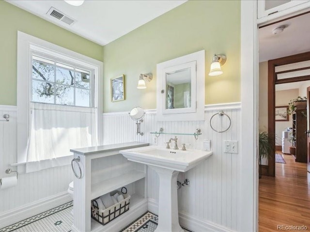 bathroom featuring a wainscoted wall and wood finished floors