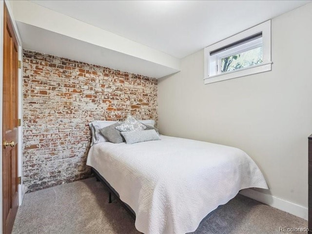 carpeted bedroom with brick wall and baseboards