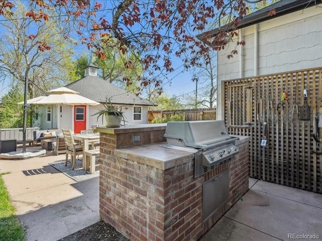 view of patio with an outdoor kitchen, a grill, and fence