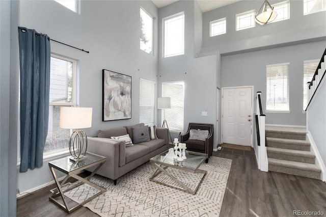 living room featuring dark wood-type flooring, a towering ceiling, and a healthy amount of sunlight