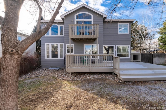 rear view of property featuring a balcony and a wooden deck