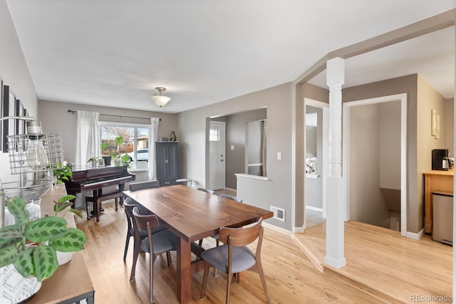 dining area featuring decorative columns and light hardwood / wood-style flooring