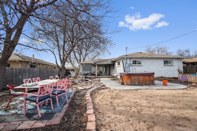 back of property with a hot tub and a patio