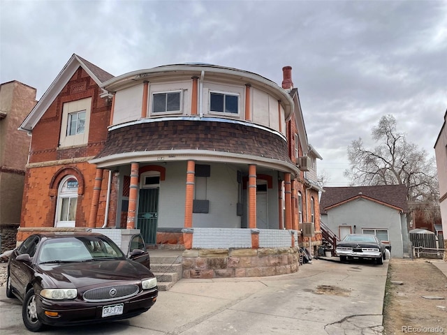 view of front of home featuring a shingled roof, a porch, and brick siding