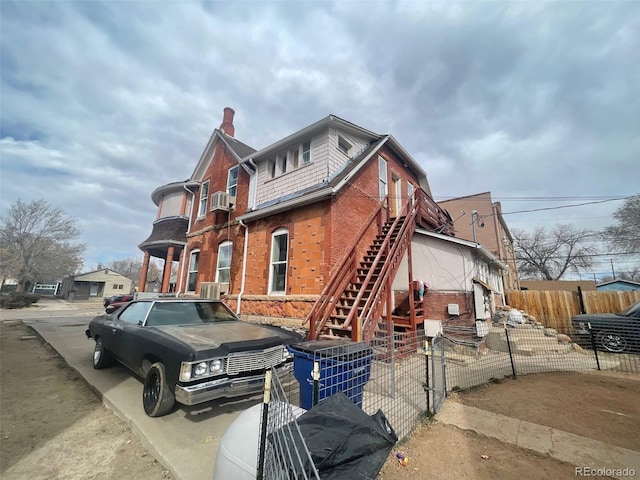 view of front of home with stairs, fence, cooling unit, and brick siding