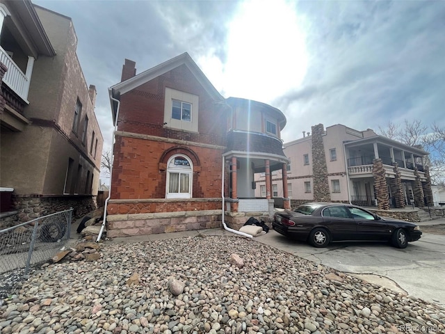 view of front facade with brick siding, fence, and a chimney