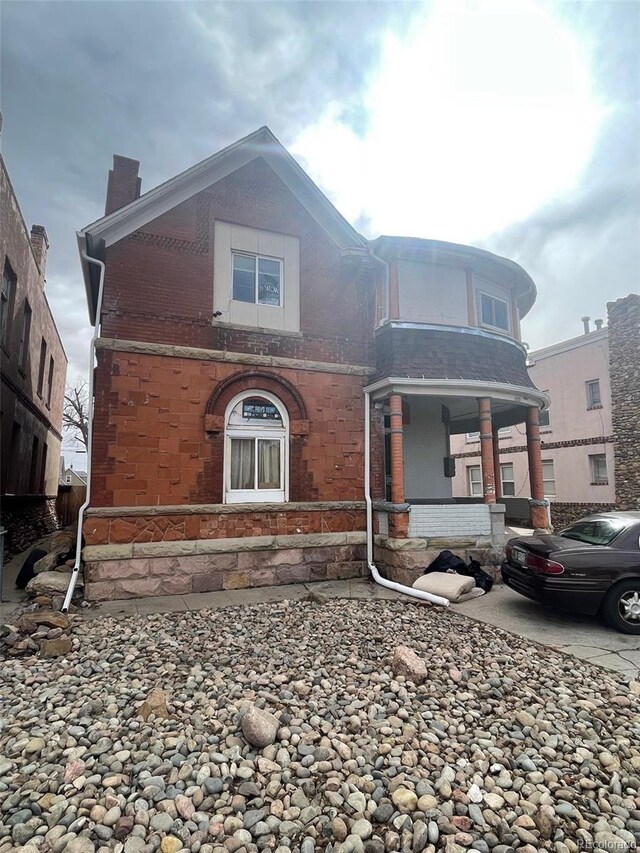 view of front of property featuring brick siding and a chimney