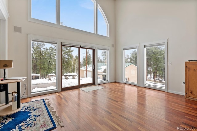 27987 Pine Grove Trl, Conifer, CO 80433 - doorway to outside featuring a high ceiling, hardwood / wood-style flooring, and baseboards