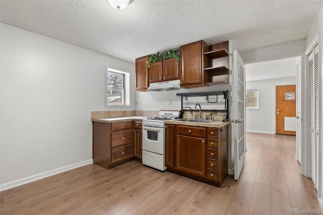 27987 Pine Grove Trl, Conifer, CO 80433 - kitchen featuring white range with gas stovetop, open shelves, under cabinet range hood, light countertops, and a sink