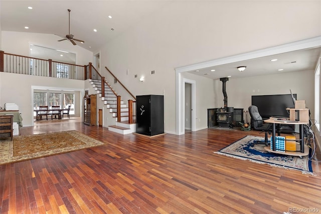 27987 Pine Grove Trl, Conifer, CO 80433 - living room featuring wood finished floors, stairway, a ceiling fan, a high ceiling, and a wood stove