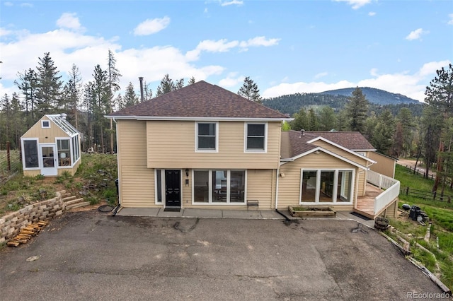 27987 Pine Grove Trl, Conifer, CO 80433 - back of house featuring a mountain view, a patio, roof with shingles, and a forest view