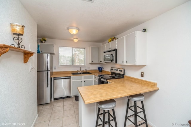 8654 Decatur St Unit 251, Westminster, CO 80031 - kitchen with stainless steel appliances, a sink, a peninsula, a kitchen bar, and light tile patterned floors