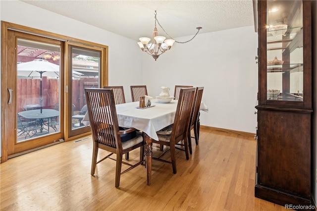 12522 W Virginia Ave, Lakewood, CO 80228 - dining area with a chandelier, light wood-style flooring, and a textured ceiling
