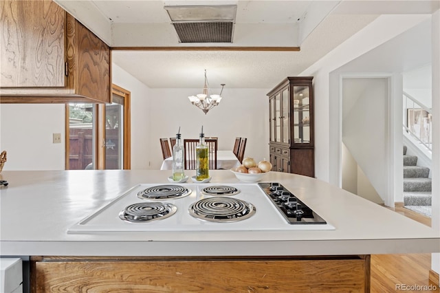 12522 W Virginia Ave, Lakewood, CO 80228 - kitchen with electric cooktop, a chandelier, light countertops, and hanging light fixtures