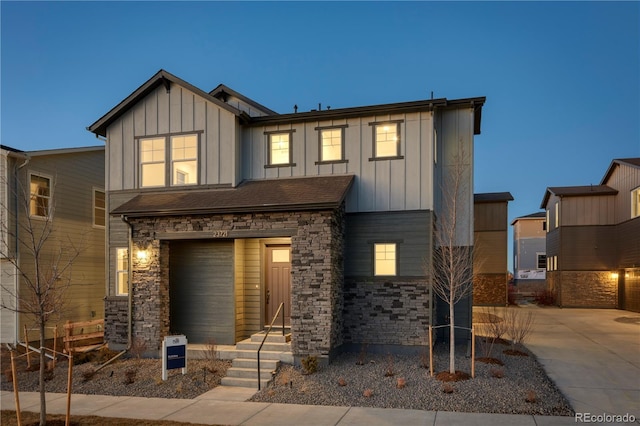 back of house featuring board and batten siding, stone siding, and driveway