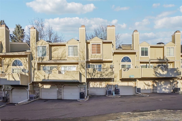 view of property with a garage, central AC, and driveway