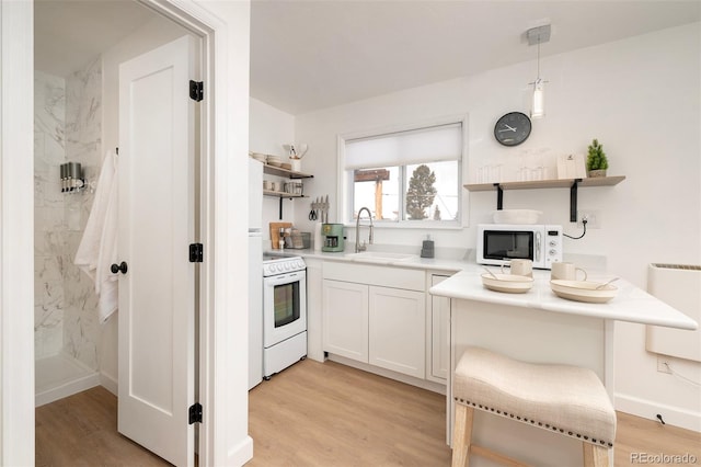 kitchen featuring light hardwood / wood-style floors, white cabinets, sink, white appliances, and pendant lighting