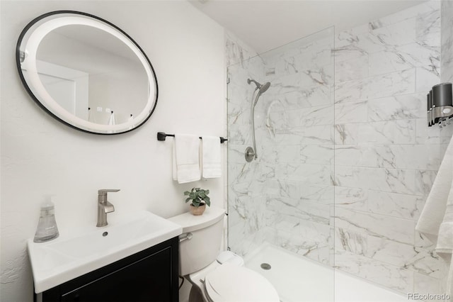 bathroom featuring a tile shower, vanity, and toilet