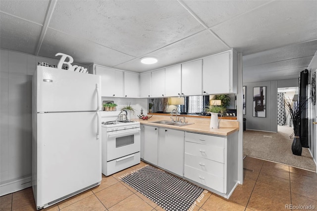 kitchen with white cabinets, white appliances, a paneled ceiling, sink, and light colored carpet