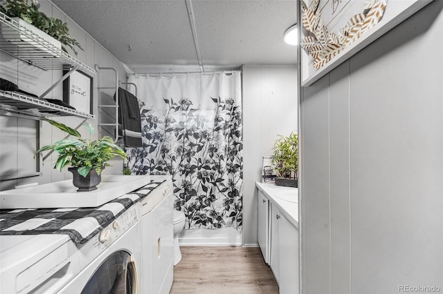 washroom featuring separate washer and dryer, a textured ceiling, and light hardwood / wood-style floors