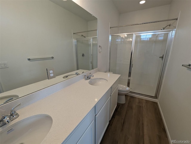 bathroom with a shower with door, vanity, wood-type flooring, and toilet