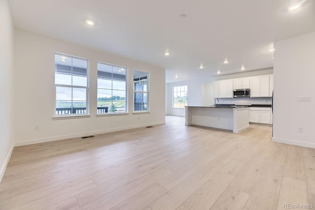 7440 S Yank Ct, Littleton, CO 80127 - kitchen with stainless steel microwave, open floor plan, dark countertops, white cabinetry, and recessed lighting