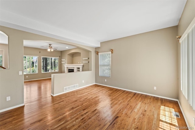 4960 Seton Pl, Colorado Springs, CO 80918 - unfurnished living room featuring wood finished floors, a fireplace, a ceiling fan, and arched walkways