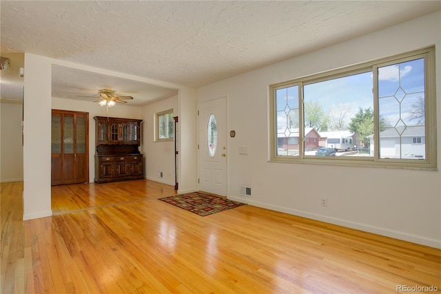 entryway with a ceiling fan, baseboards, visible vents, light wood-style flooring, and a textured ceiling