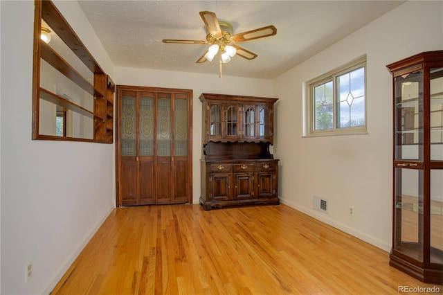 unfurnished dining area with visible vents, baseboards, light wood-style floors, and a ceiling fan