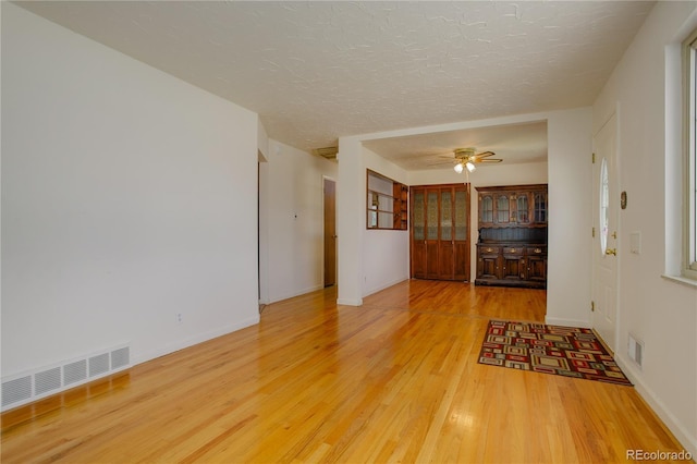 interior space with visible vents, a textured ceiling, wood finished floors, and a ceiling fan