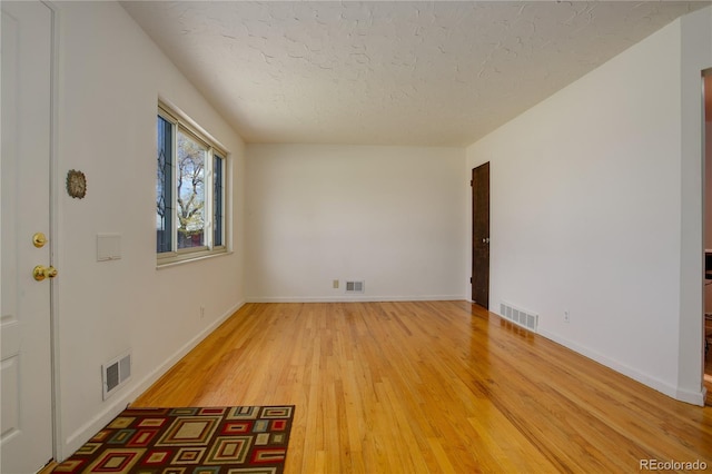 spare room featuring visible vents, a textured ceiling, and light wood-style floors