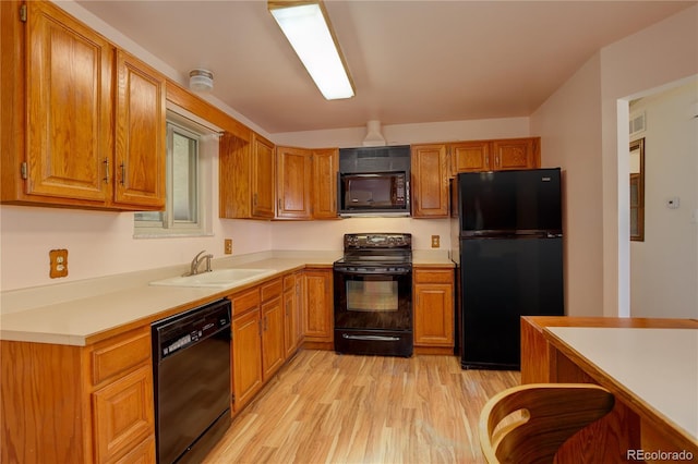 kitchen featuring a sink, brown cabinets, black appliances, and light wood-style flooring