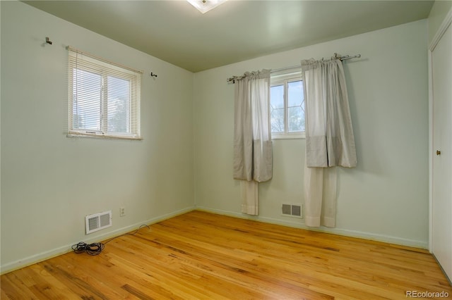 spare room with light wood-style floors, visible vents, and baseboards