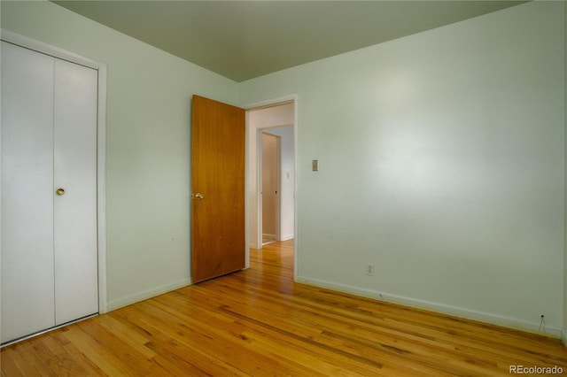 unfurnished bedroom with a closet, baseboards, and light wood finished floors